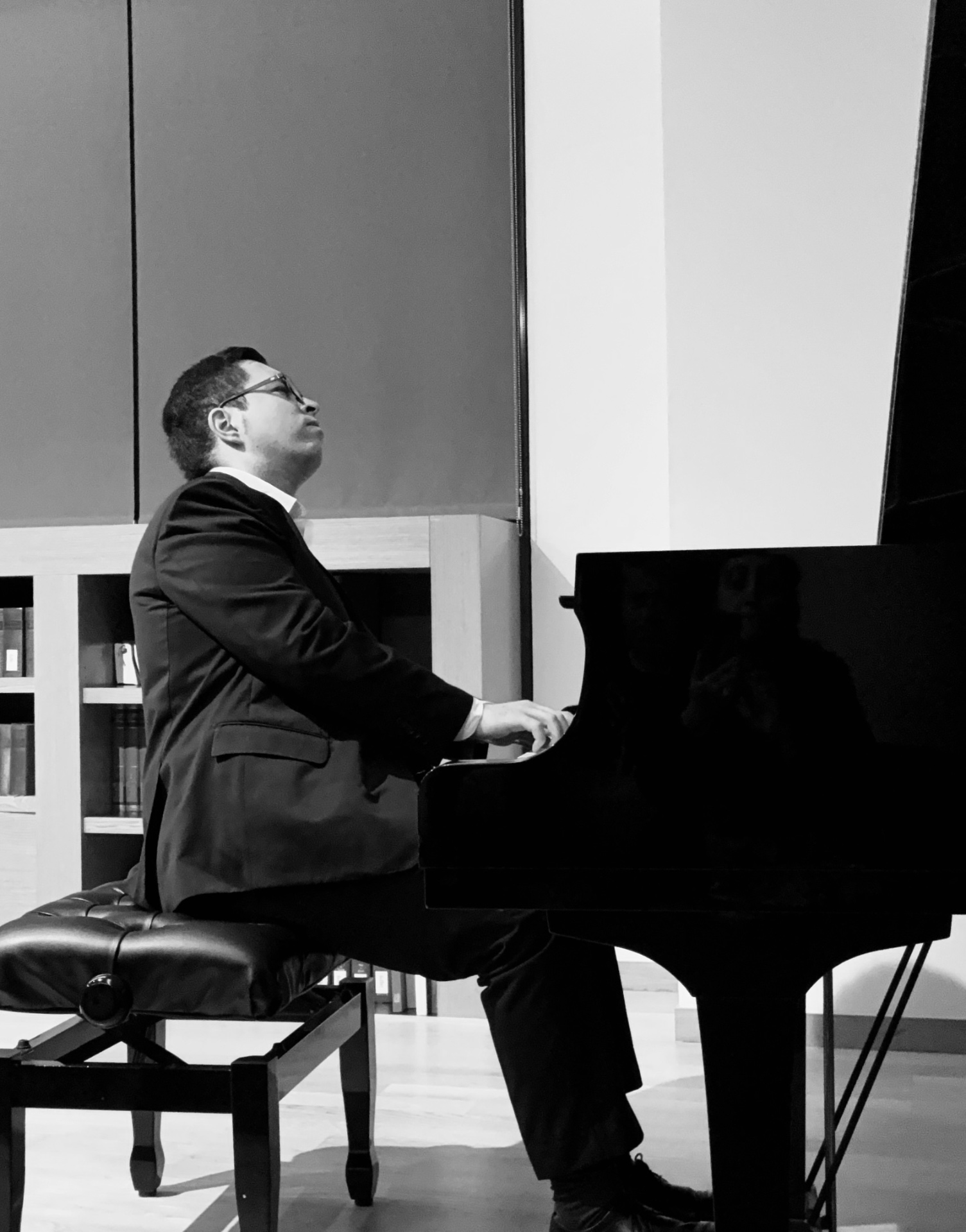 Lefteris Gavalas performing at a grand piano in a library hall