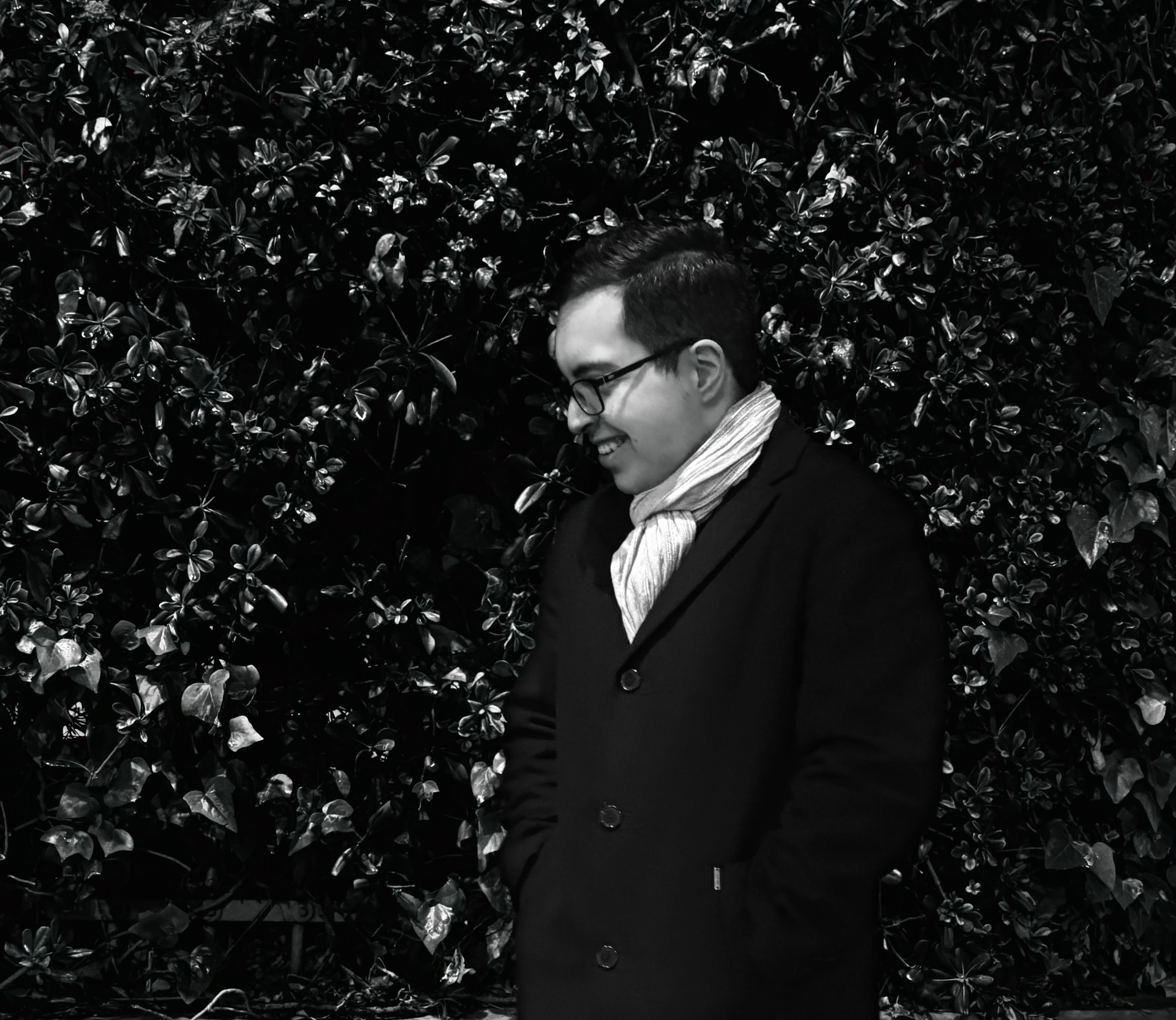 Lefteris Gavalas smiling in front of a dark leafy wall